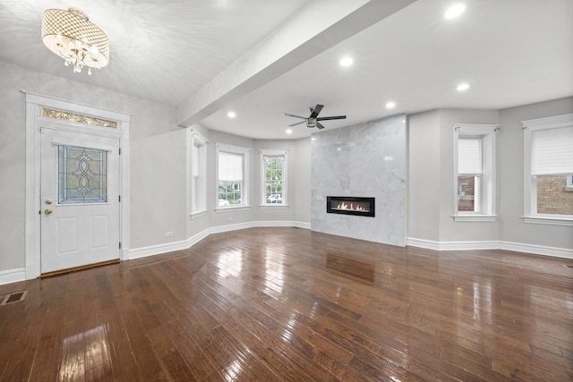 unfurnished living room with dark hardwood / wood-style floors, a fireplace, and ceiling fan with notable chandelier