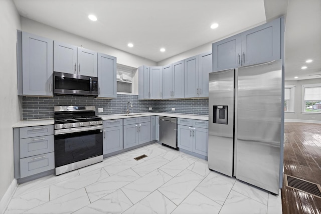 kitchen featuring gray cabinetry, decorative backsplash, sink, and stainless steel appliances