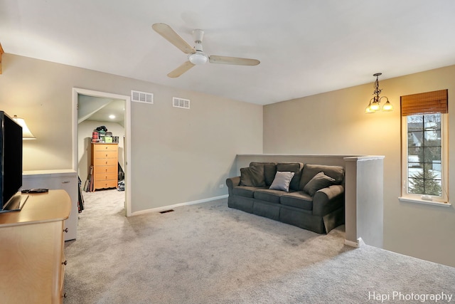 carpeted living room with ceiling fan with notable chandelier