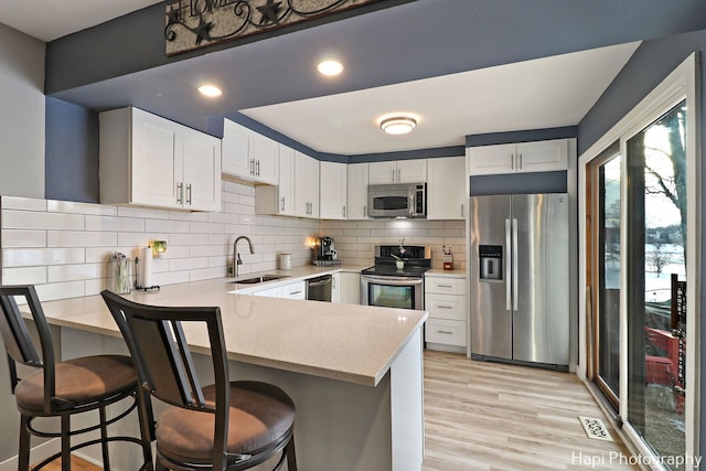 kitchen with sink, stainless steel appliances, white cabinetry, and a kitchen bar