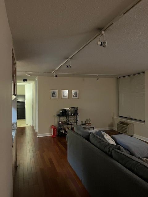 living room featuring a textured ceiling, a wall mounted AC, track lighting, and hardwood / wood-style floors