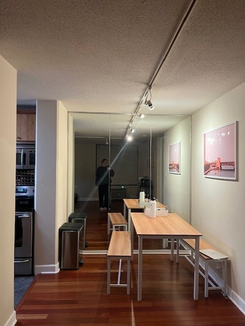 dining area with track lighting, a textured ceiling, and dark hardwood / wood-style floors