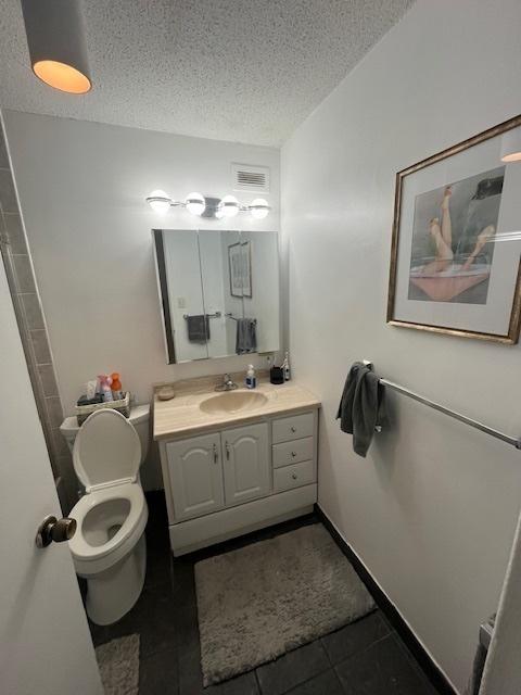 bathroom featuring toilet, tile patterned flooring, vanity, and a textured ceiling