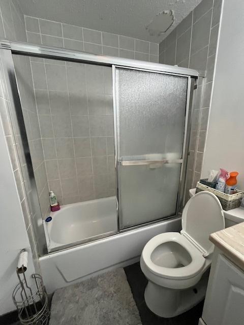 full bathroom with toilet, vanity, and shower / bath combination with glass door