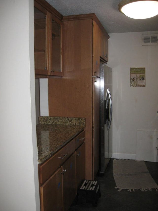 kitchen featuring dark stone countertops and stainless steel refrigerator with ice dispenser