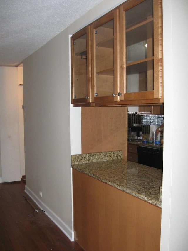 kitchen with light stone counters, a textured ceiling, black dishwasher, and dark hardwood / wood-style flooring