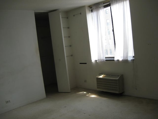 unfurnished room featuring a wall mounted air conditioner and light carpet