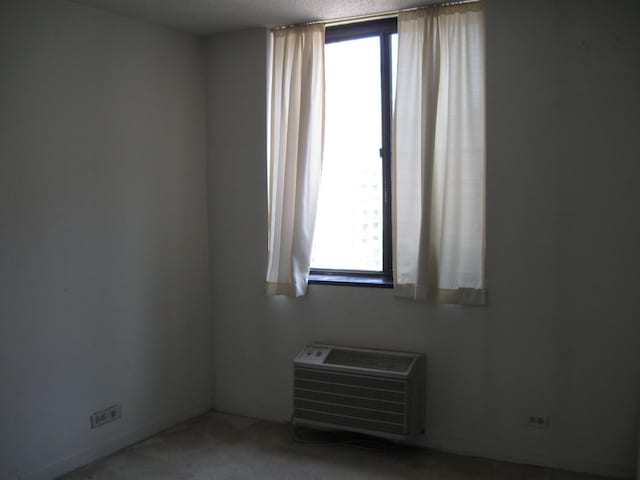 unfurnished room with a wall mounted AC and carpet floors