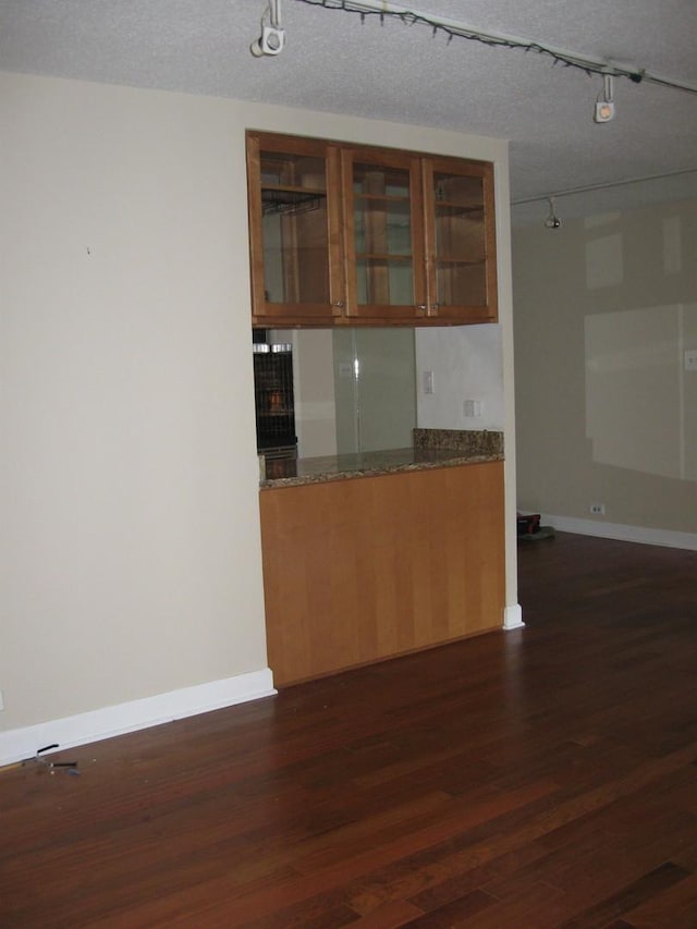 kitchen with dark hardwood / wood-style flooring, a textured ceiling, and dark stone counters