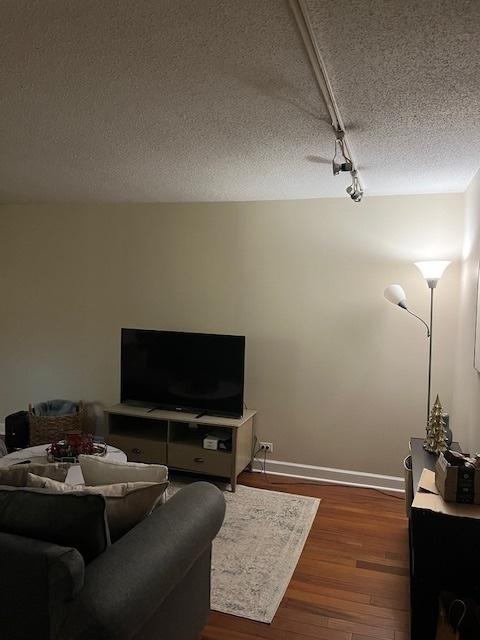 living room featuring rail lighting, a textured ceiling, and dark hardwood / wood-style floors