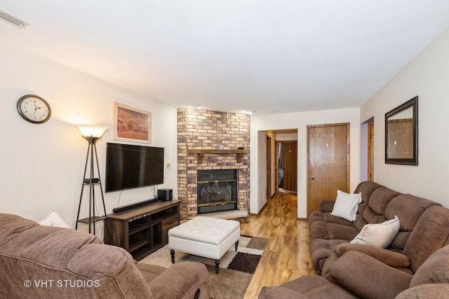 living room featuring a brick fireplace and light hardwood / wood-style floors