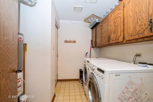 clothes washing area featuring cabinets, water heater, and washer and dryer