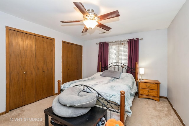 carpeted bedroom featuring multiple closets and ceiling fan