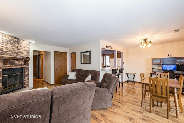 living room featuring an inviting chandelier, a fireplace, and light hardwood / wood-style floors