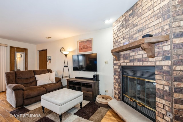 living room featuring a brick fireplace and light hardwood / wood-style flooring