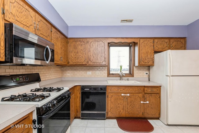 kitchen with tasteful backsplash, black dishwasher, sink, white fridge, and gas range oven