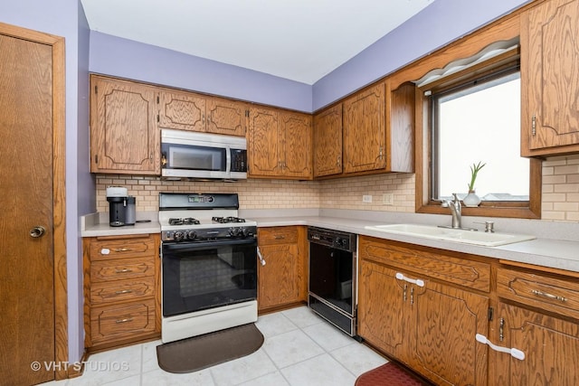 kitchen featuring sink, tasteful backsplash, light tile patterned floors, dishwasher, and gas range oven