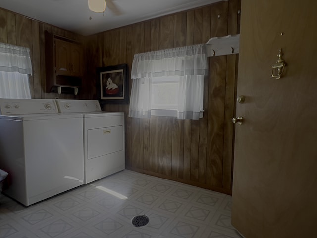 washroom with separate washer and dryer, wooden walls, and ceiling fan