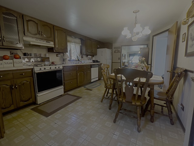 kitchen featuring white appliances, hanging light fixtures, a notable chandelier, and sink