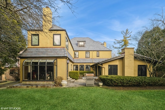 back of house with a sunroom, a patio area, and a lawn