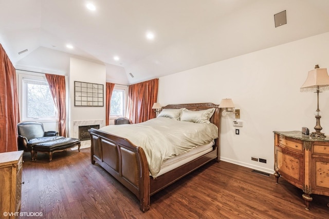 bedroom featuring dark hardwood / wood-style floors, lofted ceiling, a premium fireplace, and multiple windows