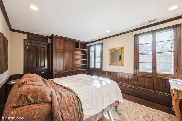 bedroom featuring wooden walls, crown molding, and wood-type flooring