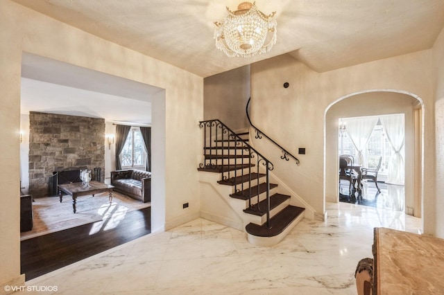 stairs featuring a fireplace and a notable chandelier