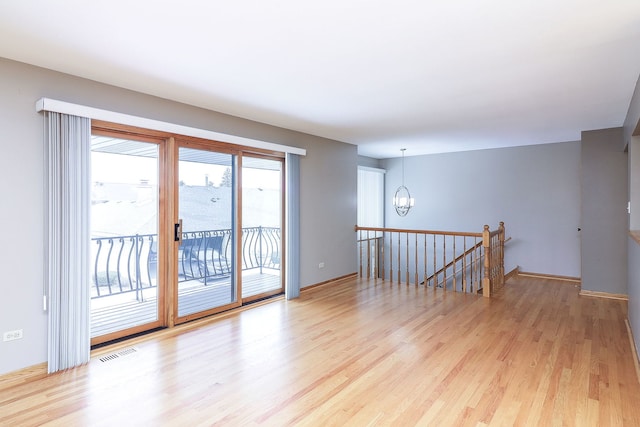 unfurnished room with a notable chandelier and light hardwood / wood-style floors