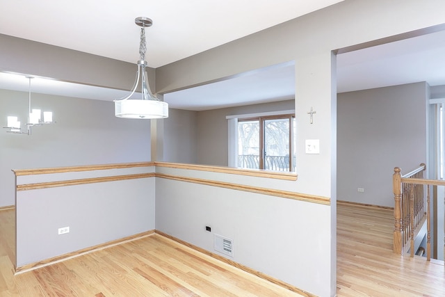 unfurnished dining area featuring a chandelier and light hardwood / wood-style floors