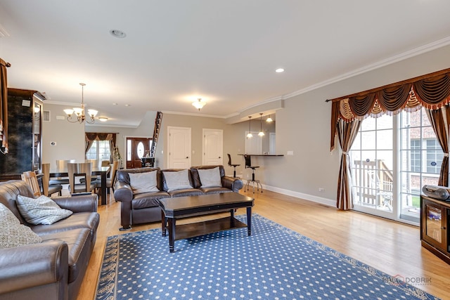 living room featuring plenty of natural light, an inviting chandelier, ornamental molding, and light hardwood / wood-style flooring