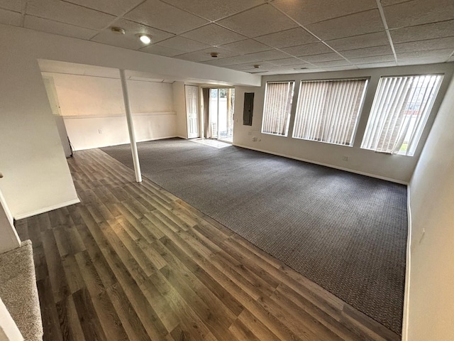 spare room featuring a paneled ceiling, plenty of natural light, dark wood-type flooring, and electric panel