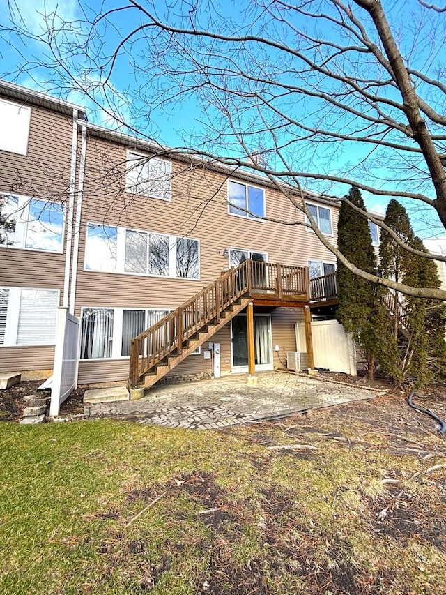 back of house with central air condition unit, a wooden deck, and a patio