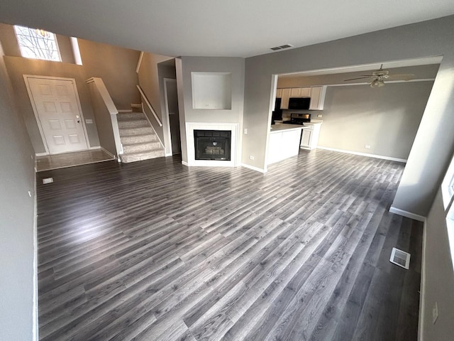 unfurnished living room with ceiling fan and dark hardwood / wood-style flooring