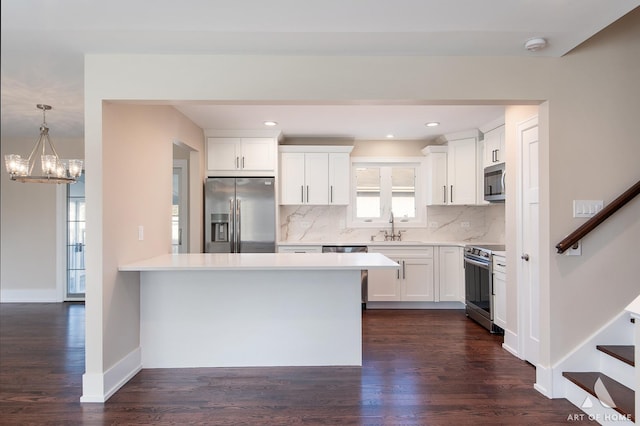 kitchen featuring sink, stainless steel appliances, dark wood-type flooring, pendant lighting, and white cabinets