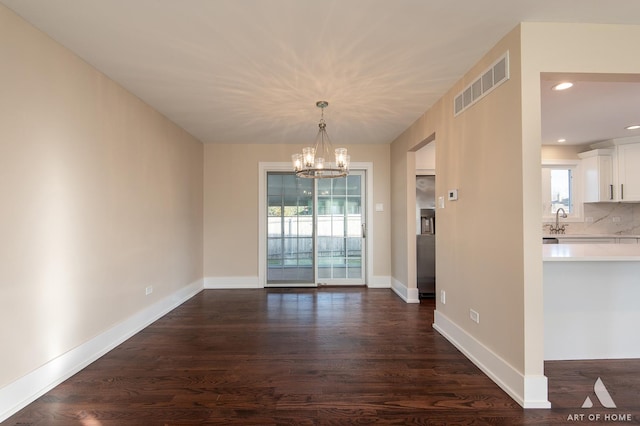 unfurnished dining area with sink, dark wood-type flooring, and a chandelier