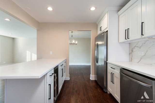 kitchen with appliances with stainless steel finishes, an inviting chandelier, tasteful backsplash, and white cabinetry