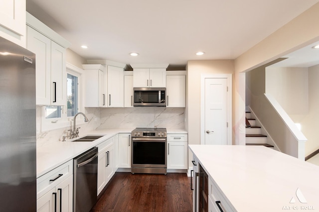 kitchen featuring decorative backsplash, appliances with stainless steel finishes, sink, white cabinets, and dark hardwood / wood-style floors