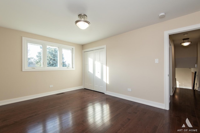 unfurnished bedroom with dark hardwood / wood-style flooring and a closet