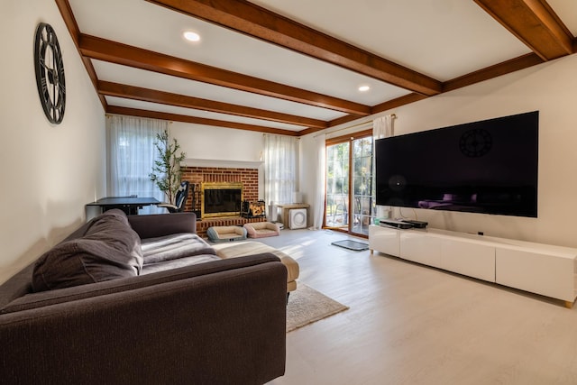 living room featuring beam ceiling, light hardwood / wood-style flooring, and a brick fireplace