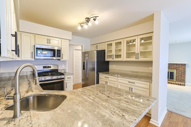 kitchen featuring a fireplace, light stone countertops, sink, and appliances with stainless steel finishes