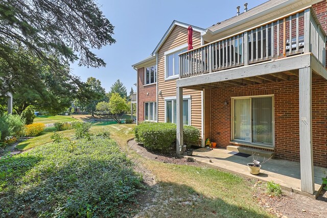 rear view of house featuring a yard and a balcony