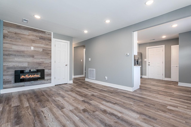 unfurnished living room featuring hardwood / wood-style floors and a tile fireplace