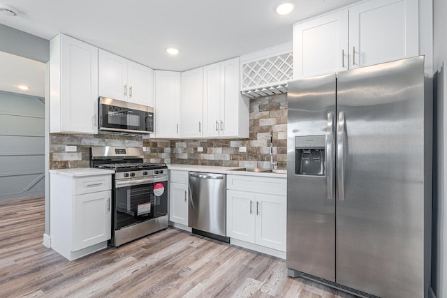 kitchen with tasteful backsplash, light hardwood / wood-style flooring, white cabinets, and stainless steel appliances