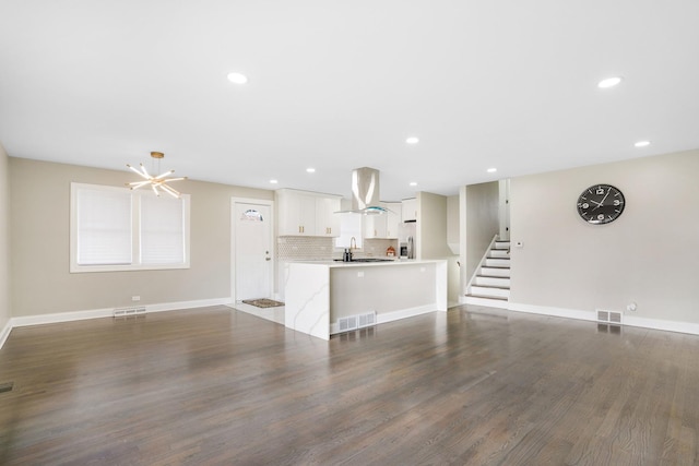 unfurnished living room with sink, an inviting chandelier, and dark hardwood / wood-style flooring