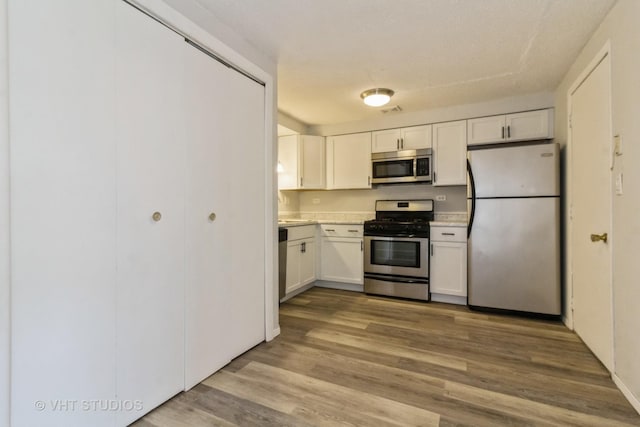 kitchen featuring white cabinetry, light wood-type flooring, and appliances with stainless steel finishes