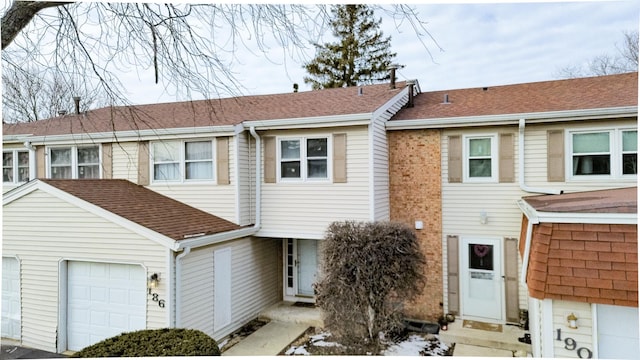 view of property featuring a garage and roof with shingles