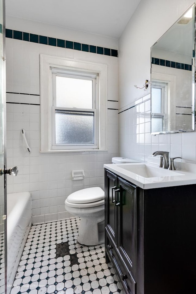 bathroom with a tub to relax in, a healthy amount of sunlight, tile walls, and toilet