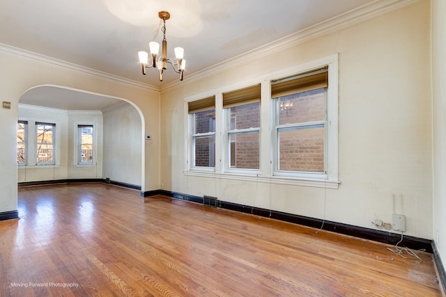 spare room with a chandelier, hardwood / wood-style floors, and ornamental molding