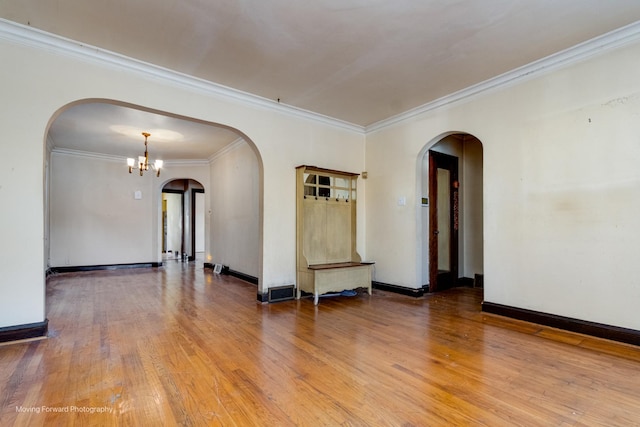 unfurnished room featuring hardwood / wood-style flooring, an inviting chandelier, and crown molding