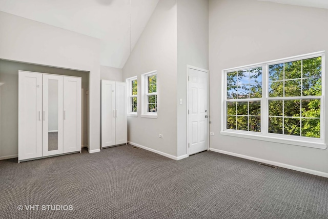 unfurnished bedroom featuring dark carpet and high vaulted ceiling